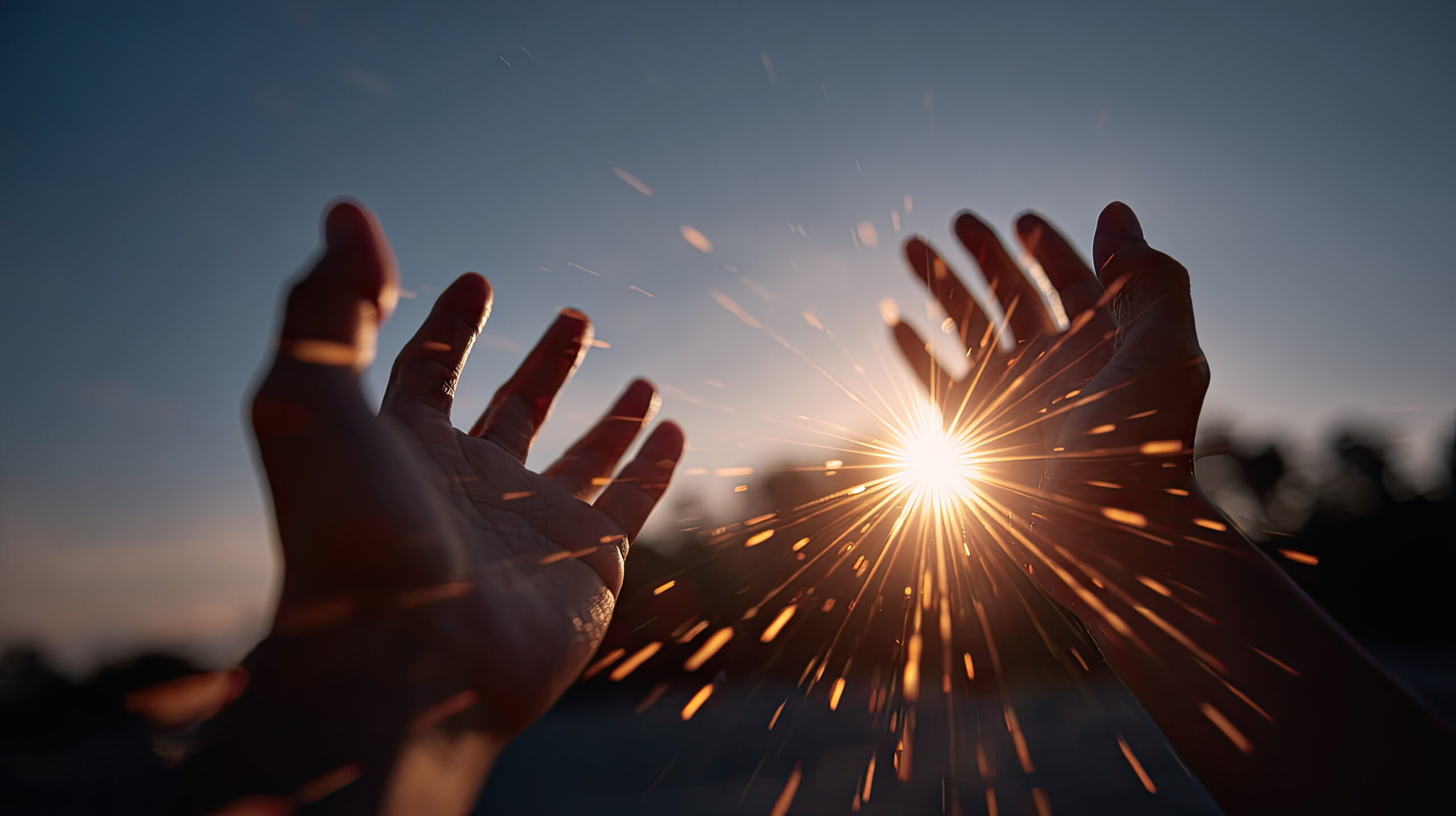 Artistic shot of hands reaching into the sky with the glowing sun behind them, flares highlighting the contours